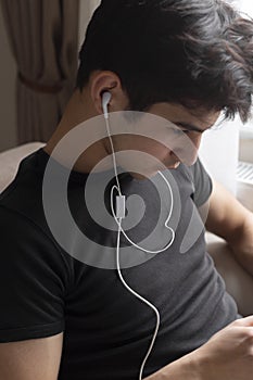 Teenage male student is studying at home, listening to music and surfing the internet