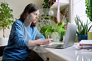 Teenage male student studying at home using a laptop