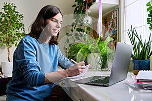 Teenage male student studying at home using a laptop