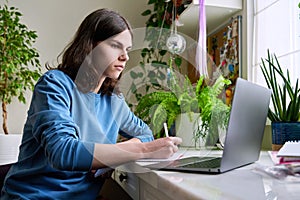 Teenage male student studying at home using a laptop