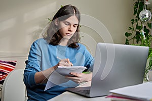 Teenage male student studying at home using a laptop