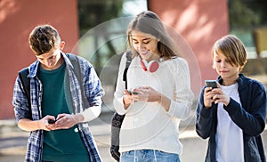 Teenage males and girl burying with mobile phones