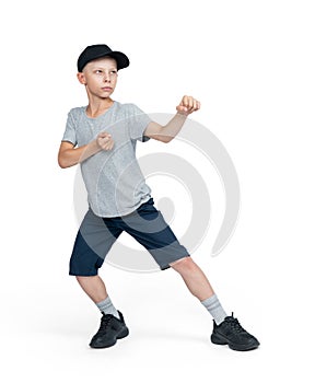 A teenage man in shorts, T-shirt, cap stands in a karate pose, isolated on a white background.