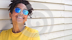 Teenage mixed race African American girl young woman wearing sunglasses reflecting blue sky and clouds