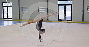 Teenage mixed race female gymnast performing at sports hall