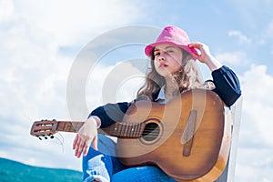 Teenage musician playing guitar. Portrait of little kid playing guitar on sky background. summer romantic playlist