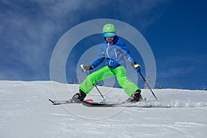 Teenage person ski on a snowy slope with blue sky in backdrop