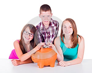 Teenage putting coins into big piggy bank