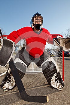 Teenage road hockey goalie outside on street