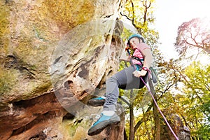 Teenage rock climber exercising at sunny day