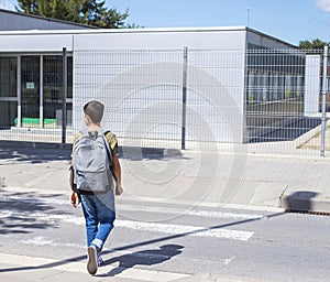 Teenage school boy with a backpack on his back walking to school