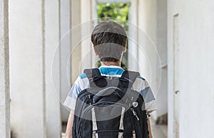 Teenage school boy with a backpack on his back walking to school