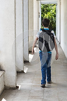 Teenage school boy with a backpack on his back walking to school