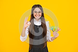 Teenage school girl with scissors, isolated on yellow background. Child creativity, arts and crafts, diy tools.