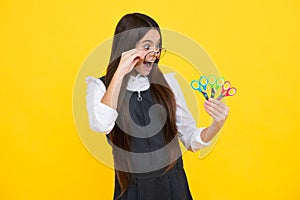 Teenage school girl with scissors,  on yellow background. Child creativity, arts and crafts, diy tools.