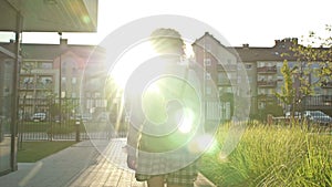 Teenage schoolgirl, college student, or high school student is returning from class. Back view.