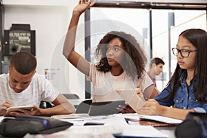 Teenage schoolgirl raising hand in class