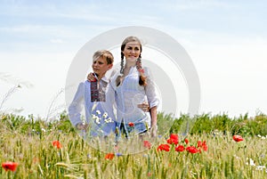 Teenage sister and little brother together on summer wheat fields