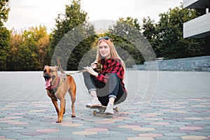 Teenage skater girl having fun with her dog in the city.