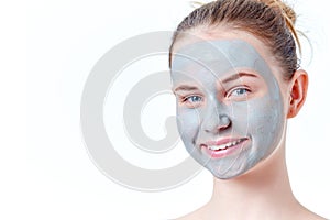 Teenage skincare concept. Smiling young redhead girl with dried clay facial mask portrait, isolated on white background.