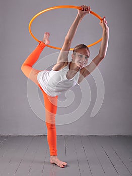 Teenage sportive girl is doing exercises with hula hoop t on grey background. Having fun playing game . Sport healthy lifestyle co