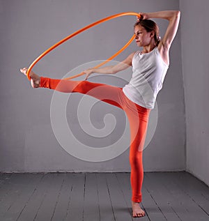 Teenage sportive girl is doing exercises with hula hoop t on grey background. Having fun playing game . Sport healthy lifestyle co