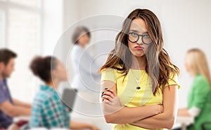 Teenage student girl in glasses pouting at school