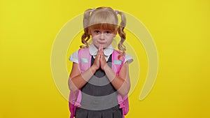 Teenage student girl kid in school uniform praying, looking upward and making wish, begging apology
