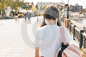 Teenage student girl walking down the street with backpack. Back to school, back view