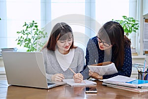 Teenage student studying at desk with computer, trainer mentor helping teaching