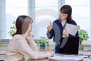 Teenage student studying at desk with computer, trainer mentor helping teaching