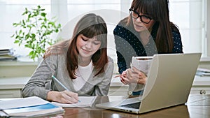 Teenage student studying at desk with computer, trainer mentor helping teaching