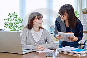 Teenage student studying at desk with computer, trainer mentor helping teaching