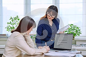 Teenage student studying at desk with computer, trainer mentor helping teaching