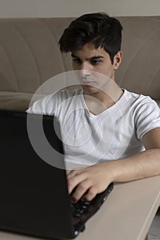 Teenage student studying at home using his tablet and computer