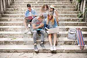 Teenage students with laptop outside on stone steps.