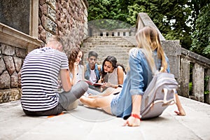 Teenage students at the stone steps in front of university.