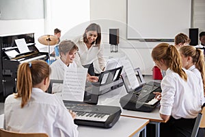 Teenage Students Studying Electronic Keyboard In Music Class