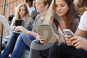 Teenage Students Using Digital Devices On College Campus photo