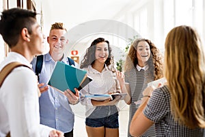 Teenage students walking in high school hall, talking.