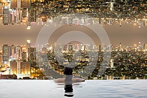 Teenage in swimming pool with city upside down