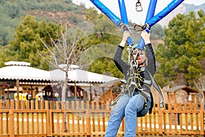Teenage teen girl bungee flying in rope amusement park. Climbing harness equipment, green sports safety helmet