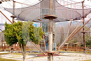 Teenage teen girl in climbing harness equipment, green sports safety helmet. Rope amusement park. Fastening