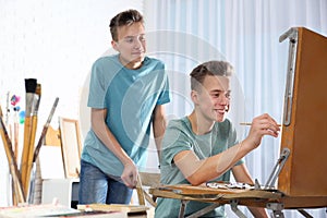 Teenage twin brothers having painting class in workshop