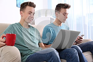 Teenage twin brothers together on sofa