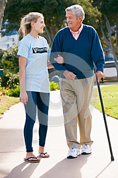 Teenage Volunteer Helping Senior Man ToWalk