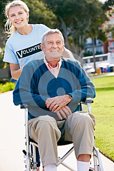 Teenage Volunteer Pushing Senior Man In Wheelchair