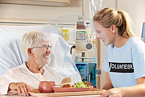 Teenage Volunteer Serving Senior Female Patient Meal