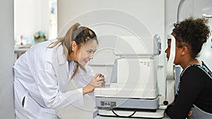 Teenage woman checking eyesight on auto refractor in ophthalmologist clinic. Eye health check and ophthalmology concept