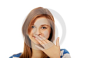 Teenage woman giggles covering her mouth with hand